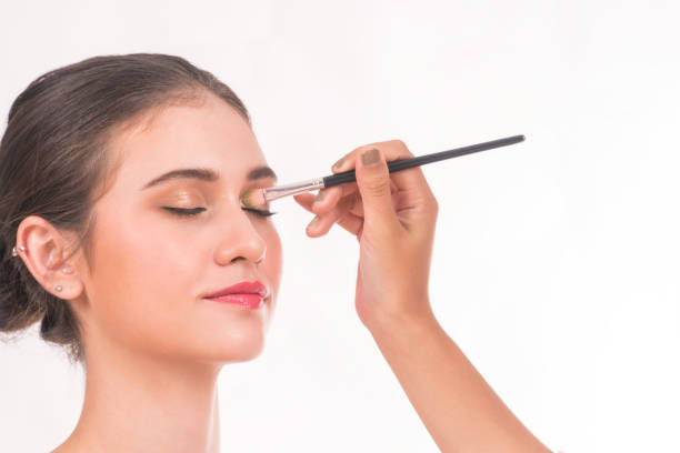 istock Makeup artist applying eyeshadow for beautiful young woman on white background. 901891884