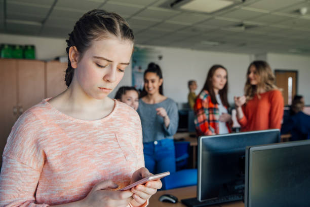 Teenage Girl Being Bullied By Text Message A teenage student is the victim of cyber bullying, looking sad harassment stock pictures, royalty-free photos & images