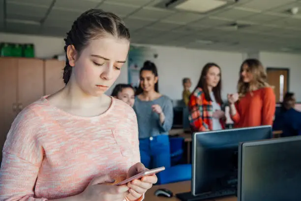 A teenage student is the victim of cyber bullying, looking sad