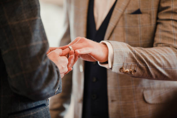 Gay Couple Exchanging Rings On Wedding Day Two men are exchanging rings on their wedding day. marriage equality stock pictures, royalty-free photos & images