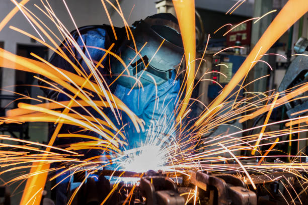 operaio sta saldando in fabbrica auto - welding sparks foto e immagini stock