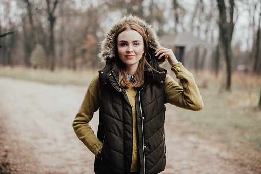Happy young woman looking in camera while standing in forest