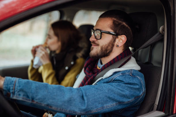 istock Man driving the car while woman eating sandwich 901904250