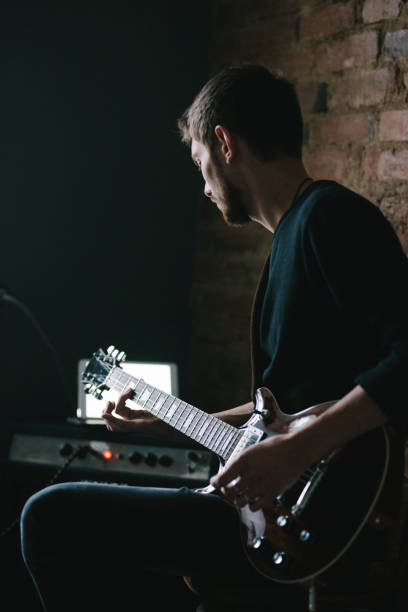 istock Young Guitarist Playing Guitar with Tablet on Amplifier 901916976