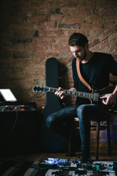istock Young Musician Playing Guitar with Tablet on Amplifier 901917018