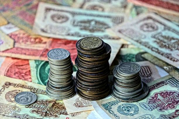 istock Old coins in piles on paper money bills 901919782