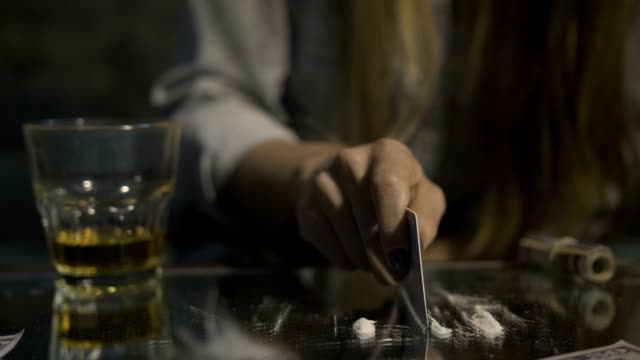 Middle section of female making coke line on table