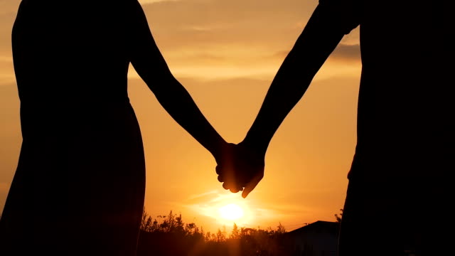 Couple separating their hands at sunset, love story ending, family break-up