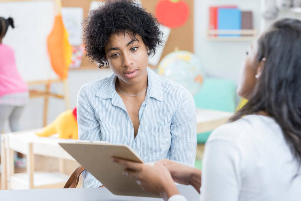 istock Young mother discusses day care paperwork with day care worker 901926582