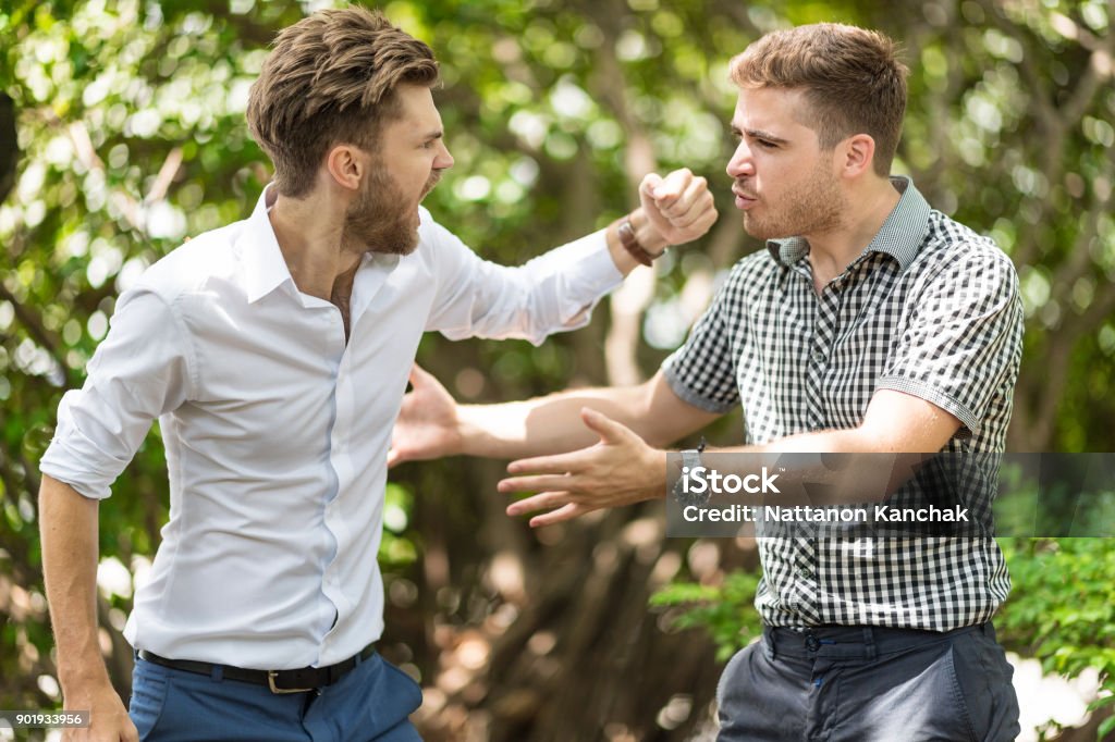 business people conflict problem Two handsome and young furious men fighting with each other in the garden. Men Stock Photo