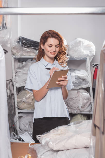 istock young female dry cleaning worker writing in notebook at warehouse 901941514