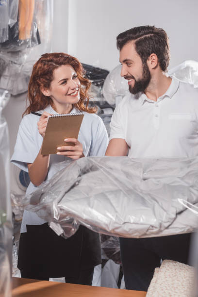istock happy dry cleaning workers with jacket in bag at warehouse 901941874