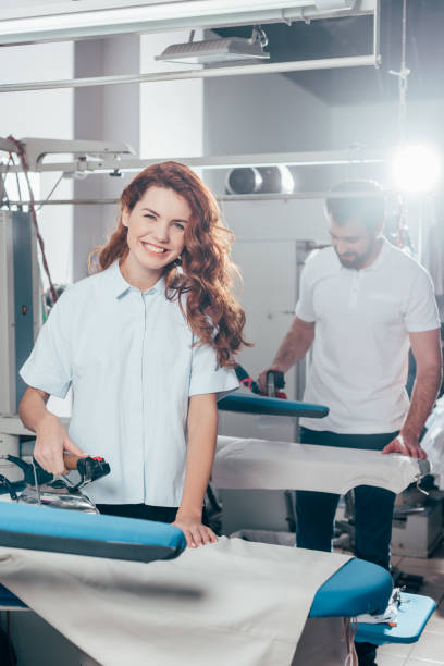 istock happy young dry cleaning workers ironing clothes together 901942486