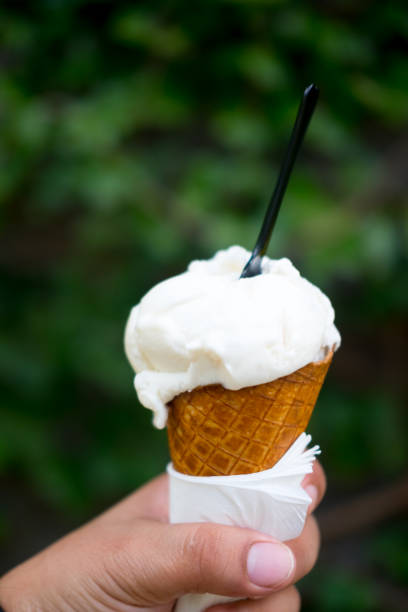 istock Closeup young man holding ice cream cone in hand with nature background 901948192