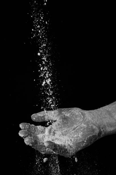 istock flour falling in mans hand, against black background 901948828