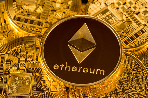 MORGANTOWN, WV - 31 DECEMBER 2017: Ethereum or ether coin lying on top of similar golden coins to illustrate cybercurrencies