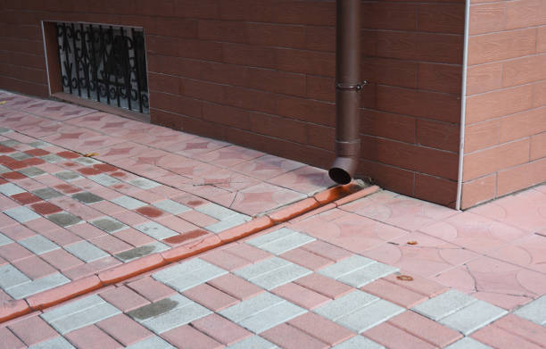 istock Roof gutter downspout pipe with drain in pavement. Rain gutter pipeline drainage. 901950134