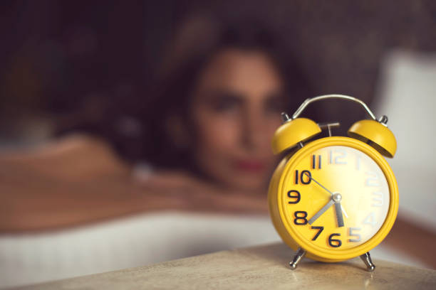 istock Alarm clock with woman relaxing on bed 901952978