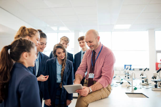 High School Lesson A male teacher talking to a group of students in a science room high school teacher stock pictures, royalty-free photos & images