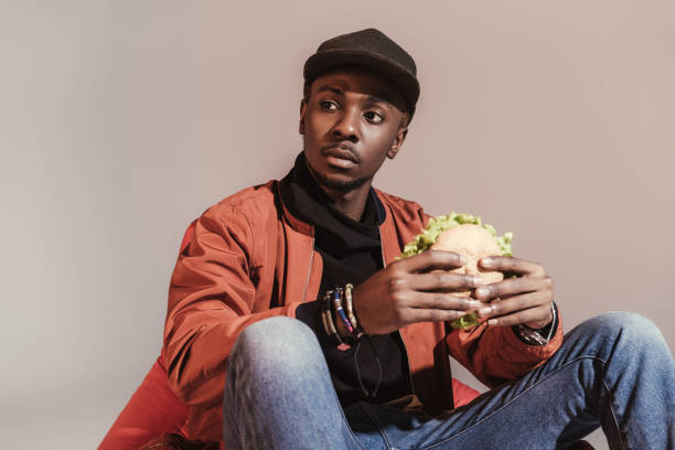 istock man eating hamburger and looking away isolated on grey 901964582