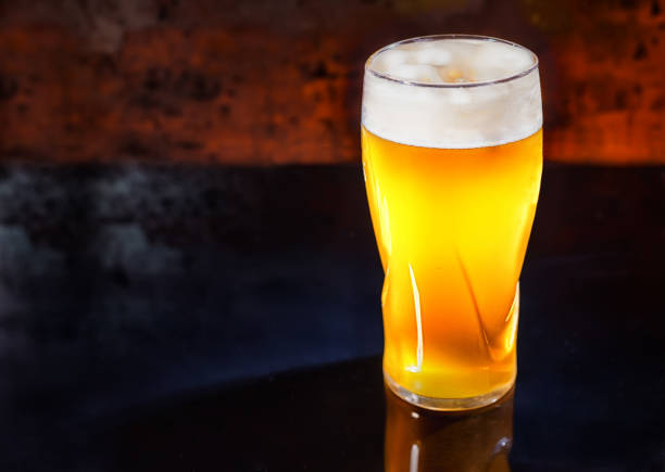 istock Glass with freshly poured unfiltered light beer on a black mirror surface 901969172