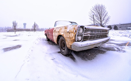 Vintage muscle car convertible in snowy winter parking lot landscape