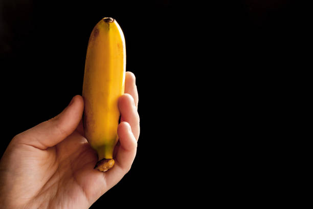 istock Hand holds banana of black background 901977674