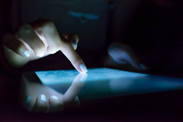 istock Woman's pointing finger with tablet glowing screen at home. 901977714