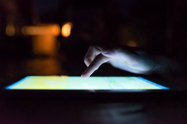 istock Woman hand hold and touch screen tablet on abstract blurred night light background. 901977926