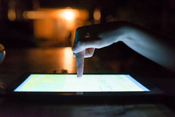 istock Woman hand hold and touch screen tablet on abstract blurred night light background. 901977928