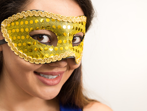 A beautiful woman wearing yellow Brazilian Carnaval mask. Headshot.