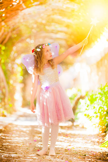 Little fairy in the woods holding a magic wand looking upwards. DSRL outdoors photo taken with Canon EOS 5D Mk II and Canon EF 70-200mm f/2.8L IS II USM Telephoto Zoom Lens