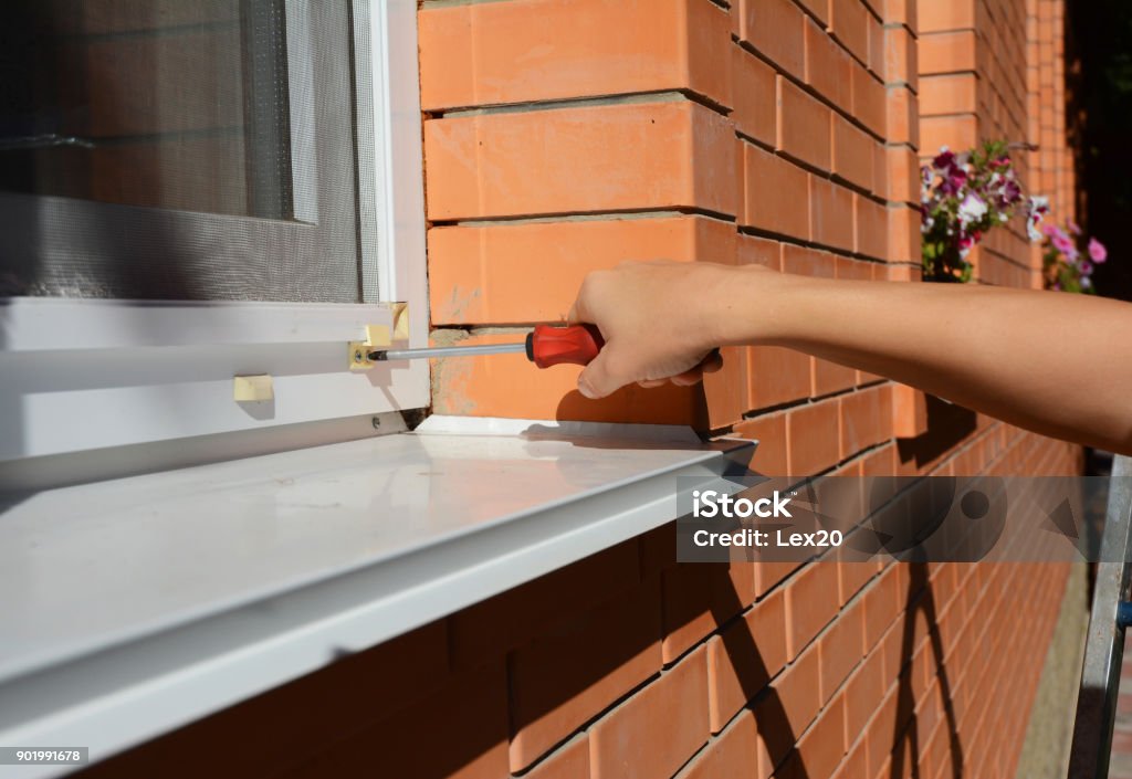 Arbeiter, Moskitonetz, Fliegengitter Draht auf Backstein Haus Fenster installieren. - Lizenzfrei Moskitonetz Stock-Foto