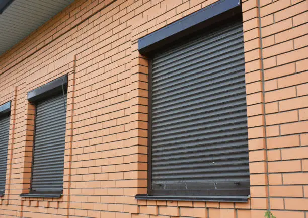 Photo of Brick House Windows with rolling shutter for house protection.
