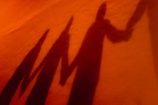 Shadows of four people holding hands stock photo