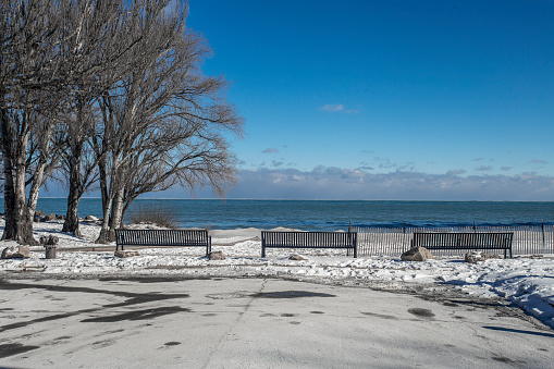 3 park benches sitting empty on snow covered beach with clear sky