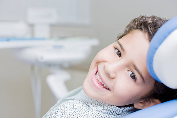 menino sorridente, sentado na cadeira de dentistas - dentists chair anticipation smiling healthcare and medicine - fotografias e filmes do acervo