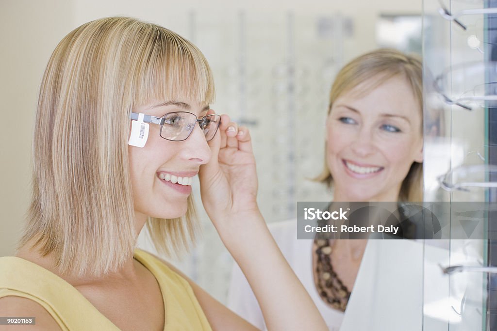 Donna cercando su occhiali in negozio optometristi - Foto stock royalty-free di Occhiali da vista
