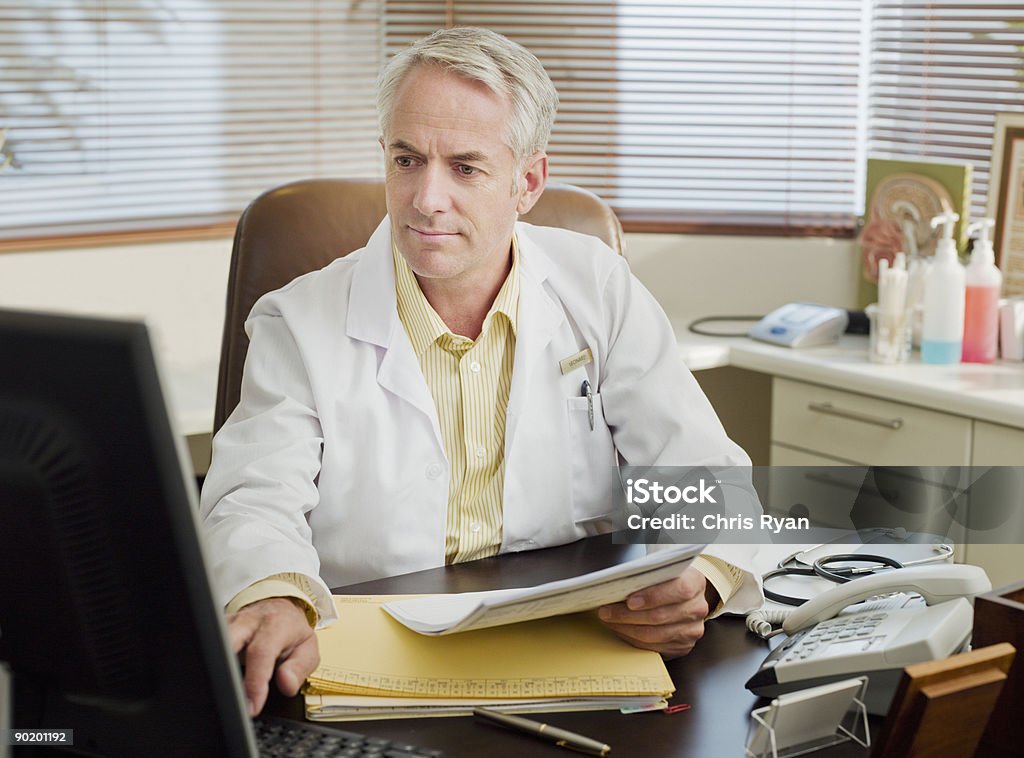 Doctor working at desk in office  45-49 Years Stock Photo