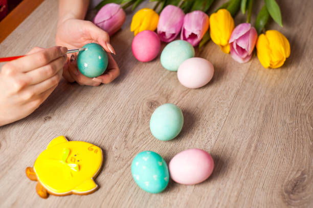 istock Hands on background wooden tablegirl paints the Easter eggs, preparing for the holiday, decor 902038470