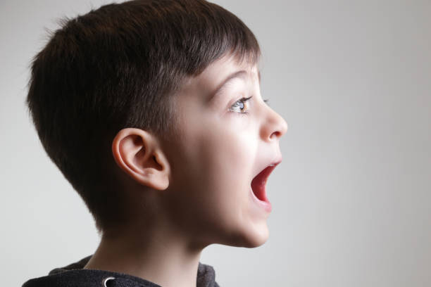 Studio portrait of cute boy screaming - side view Studio portrait of cute boy screaming - side view child laughing hysterically stock pictures, royalty-free photos & images