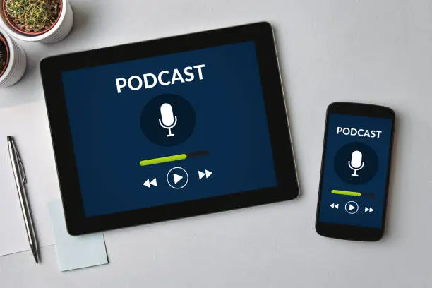 Podcast concept on tablet and smartphone screen over gray table. All screen content is designed by me. Flat lay