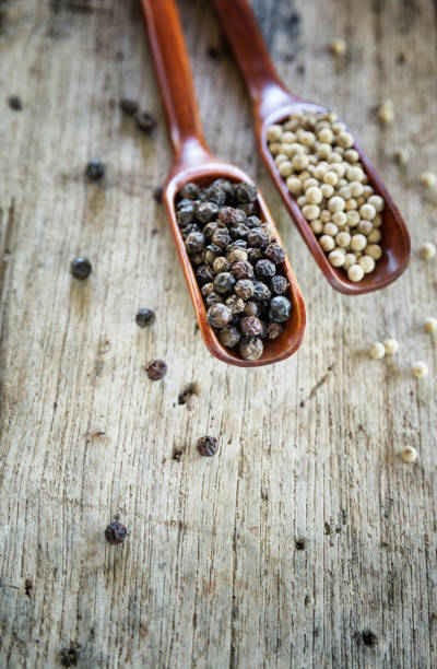 istock White pepper and black pepper on wood spoon. 902086576