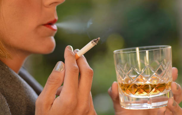 Woman drinking a glass of whiskey and smoking a cigarette. stock photo