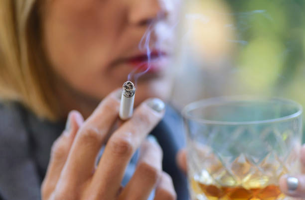 Woman drinking a glass of whiskey and smoking a cigarette. stock photo
