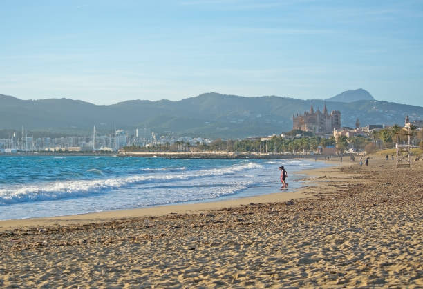 PALMA DE MALLORCA, SPAIN - JANUARY 4, 2018: Cathedral and city beach with people on a sunny winter afternoon on January 4, 2018 in Palma de Mallorca, Spain.
