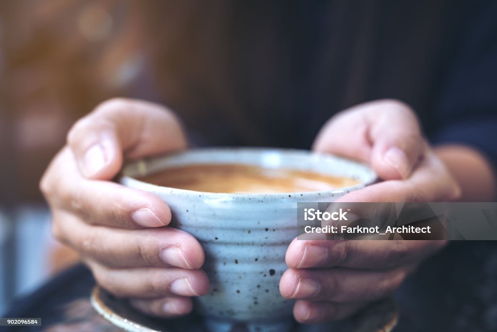 Closeup image of hands holding a cup of hot coffee on glass table in cafe Hand Stock Photo