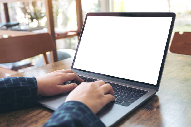 istock Mockup image of hands using and typing on laptop with blank white desktop screen on wooden table in cafe 902096632