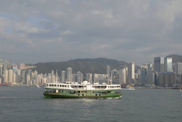 Hong Kong, China - January 21st, 2011: The iconic green and white Star Ferry chugging across the blue waters of Hong Kong Harbour overlooked by the soaring spire of 2IFC and the crowded downtown cityscape of Hong Kong Island.