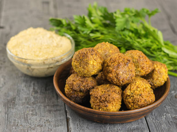 istock Freshly cooked falafel on clay bowl on a wooden table with tahini sauce. A rustic style. 902121404